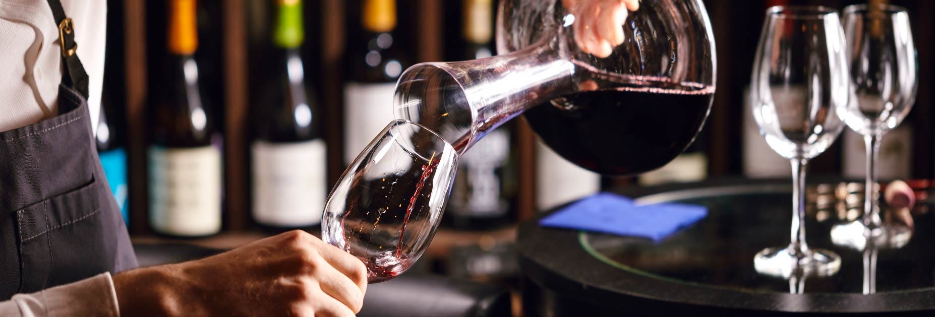 Wein fliesst aus einer Karaffe in ein Weinglas