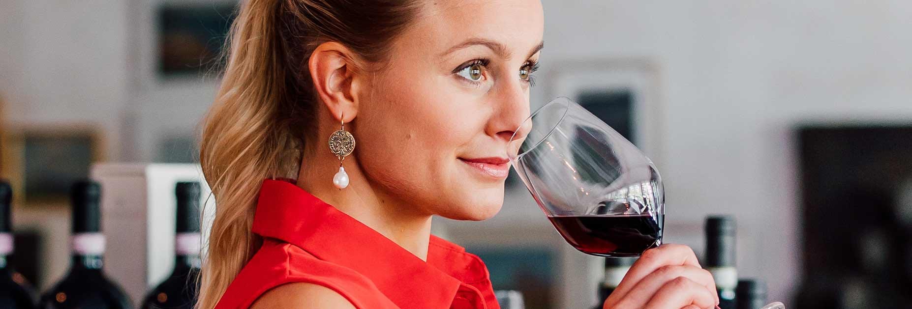 Eine junge Dame riecht an einem Glas Rotwein in der VInoteca Zürich