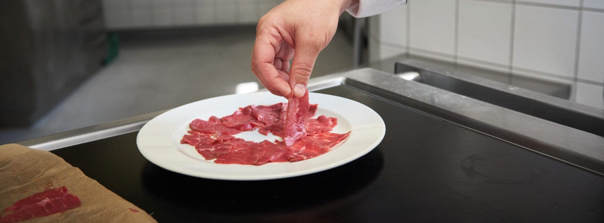 Carpaccio auf dem Teller anrichten und mit Fleur de Sel würzen.